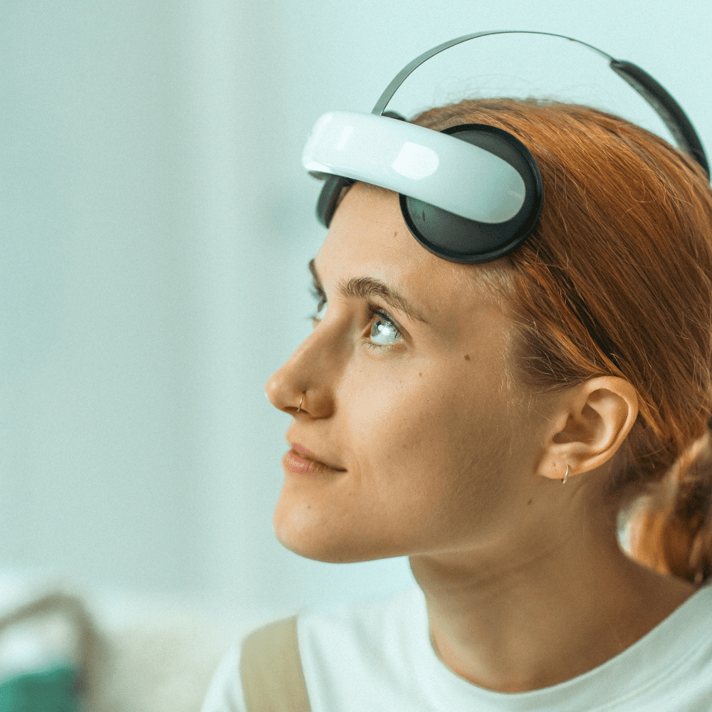 Valokuva henkilöstä, joka käyttää hoitolaitetta. Laite on aseteltu hänen otsalleen.